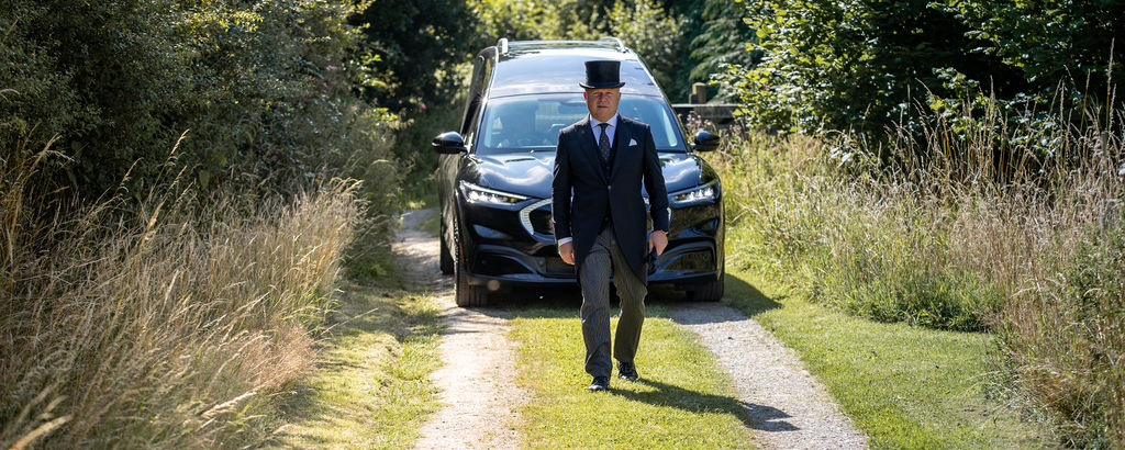 Julian Walker, Funeral Director walking in front of a hearse